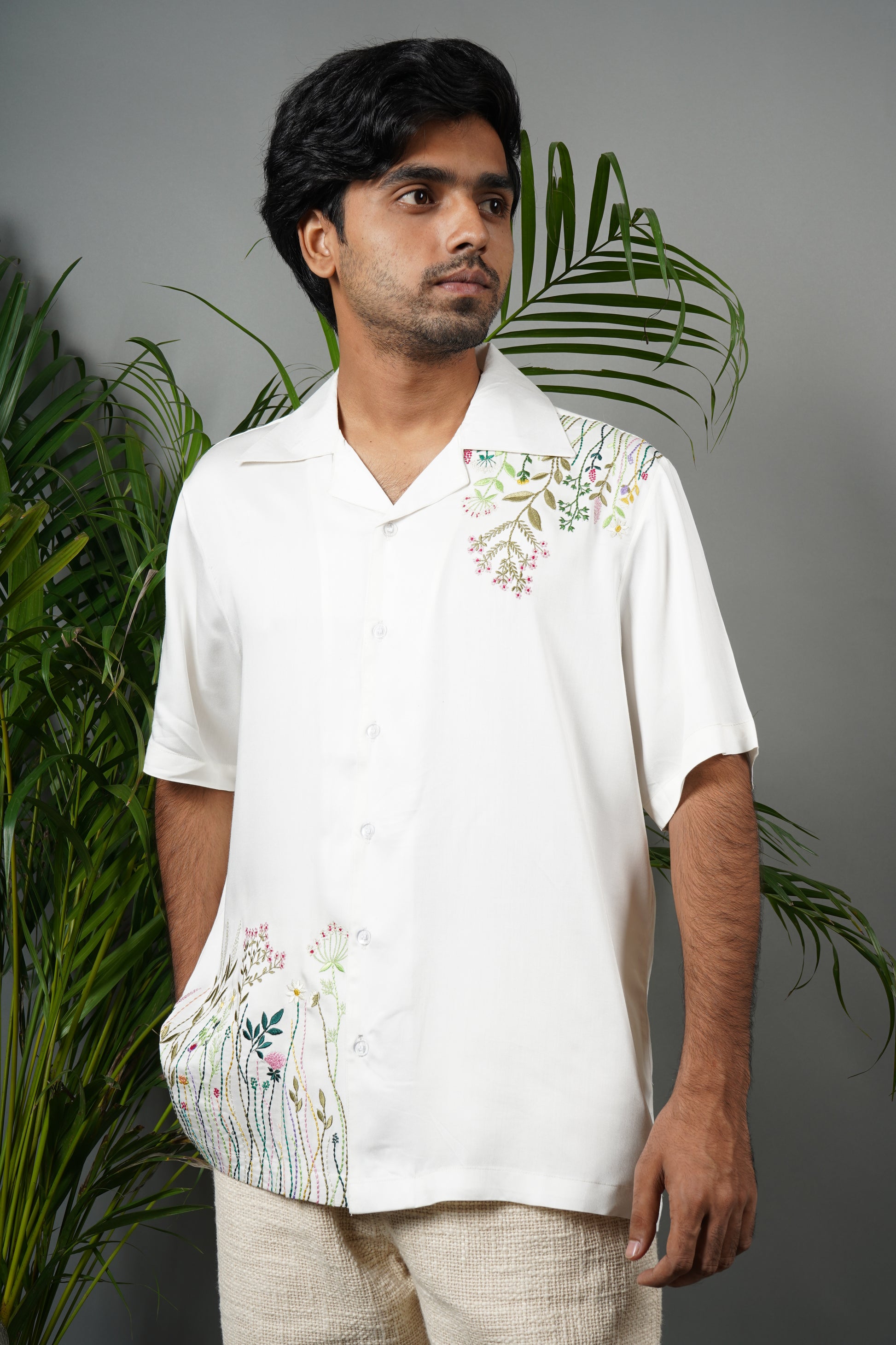 "Handmade white Cuban collar shirt made from soft modal fabric with intricate  embroidery featuring floral and leaf patterns on the shoulder and pocket."

