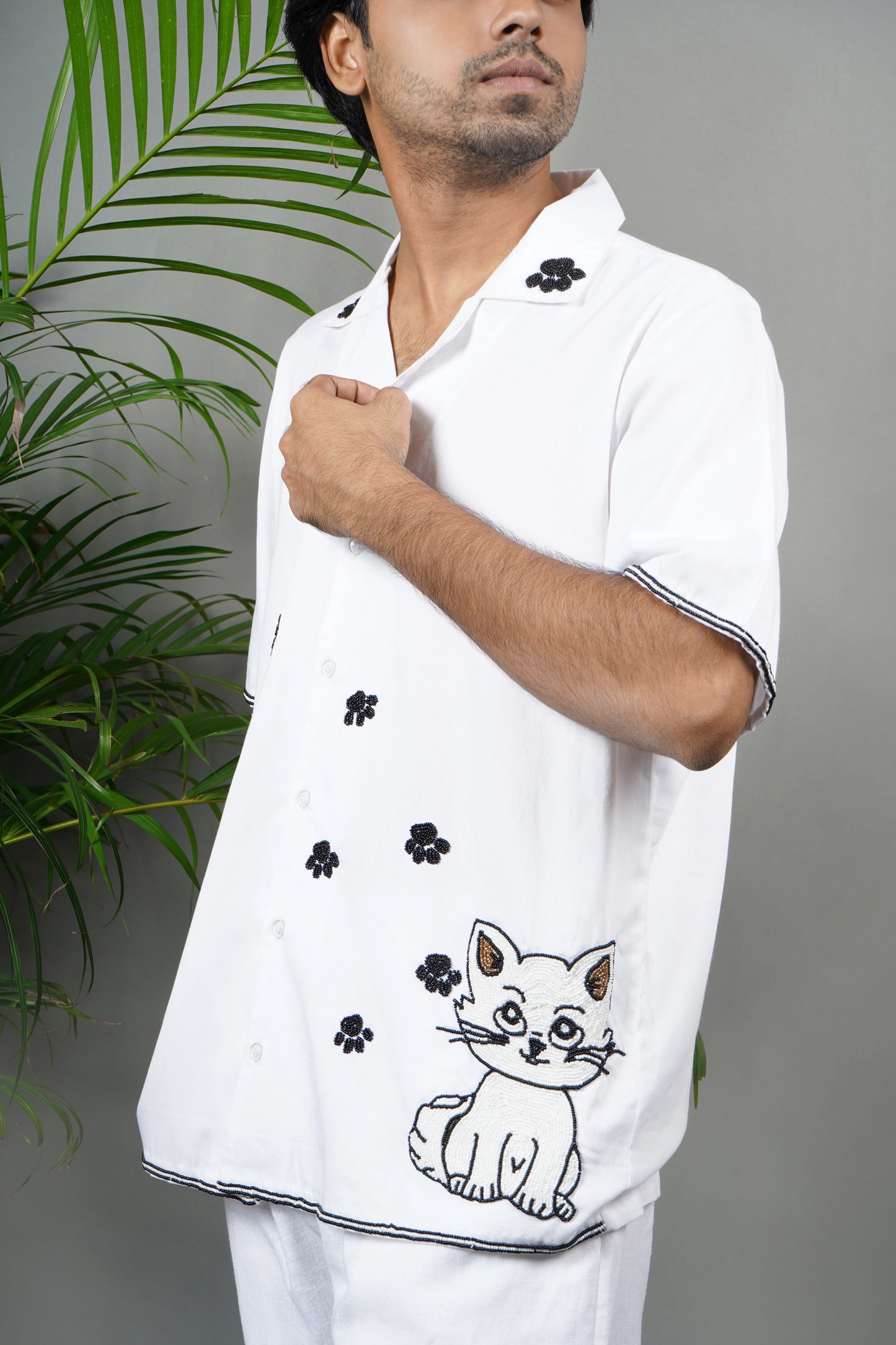 Handmade white cotton shirt with embroidered cat design and black floral accents, playful luxury embroidered shirt for men.

