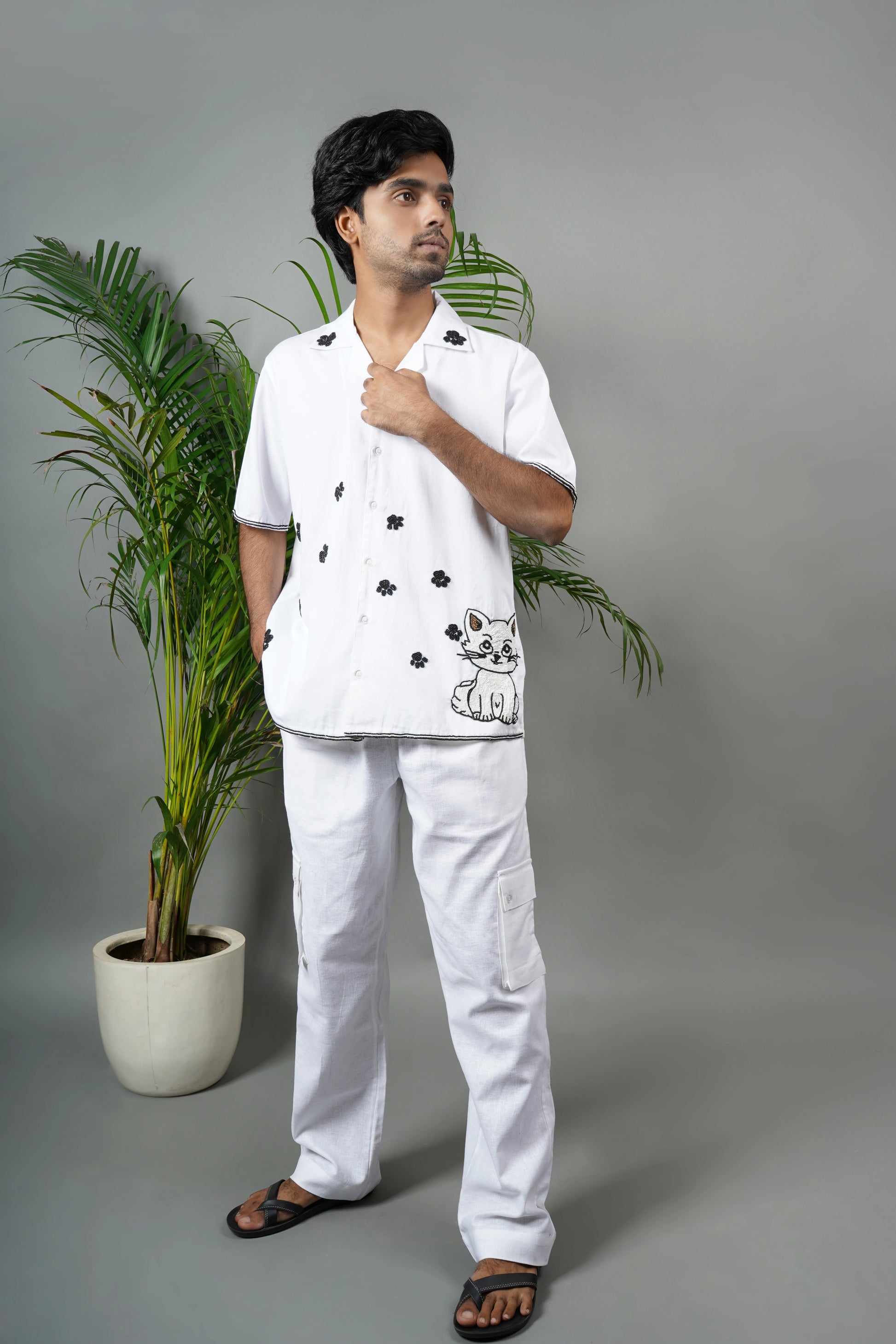 Handmade white cotton shirt with embroidered cat design and black floral accents, playful luxury embroidered shirt for men.

