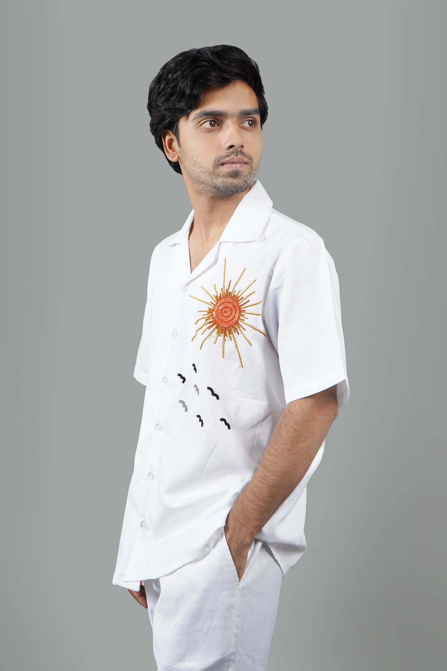 Handmade white cotton shirt with vibrant hand-embroidered tropical palm tree and sun design, luxury summer wear for men, unique artisanal embroidery.

