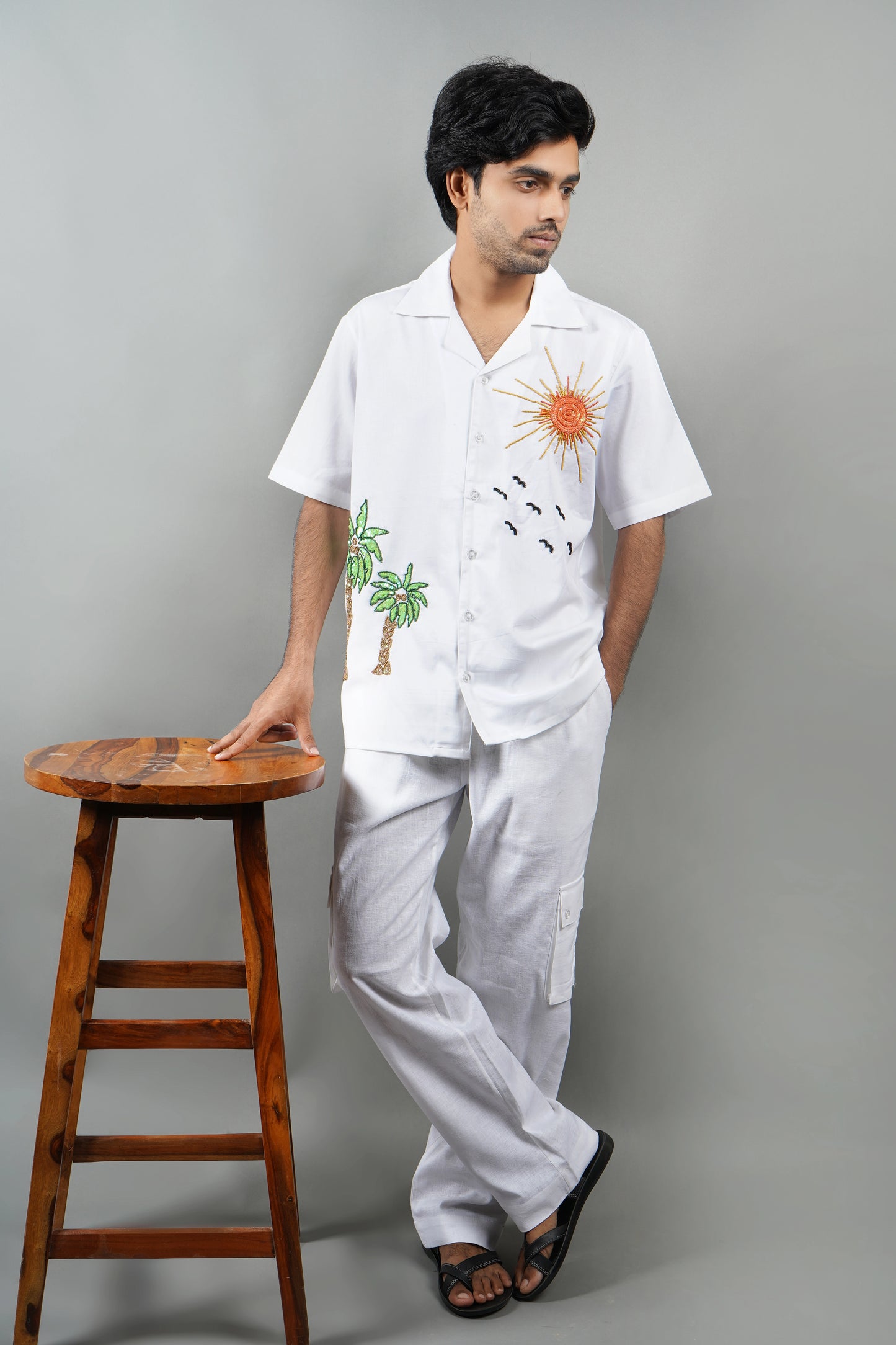 Handmade white cotton shirt with vibrant hand-embroidered tropical palm tree and sun design, luxury summer wear for men, unique artisanal embroidery.

