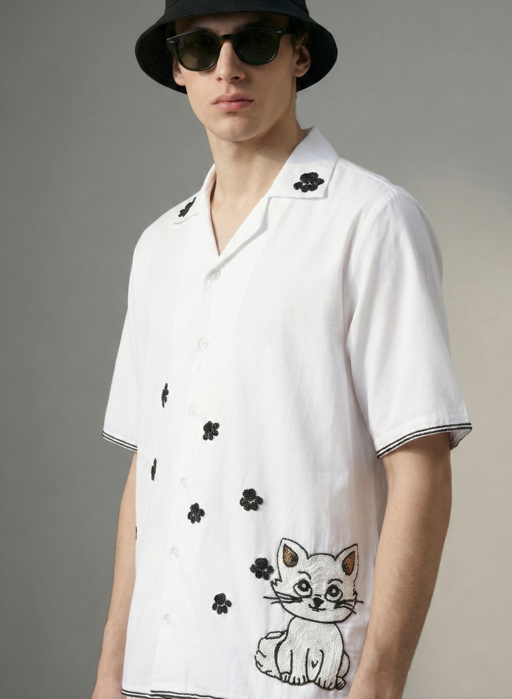 Close up of mens white cotton Cuban collar shirt with black paw print embroidery, handmade designer summer resort wear shirt for men