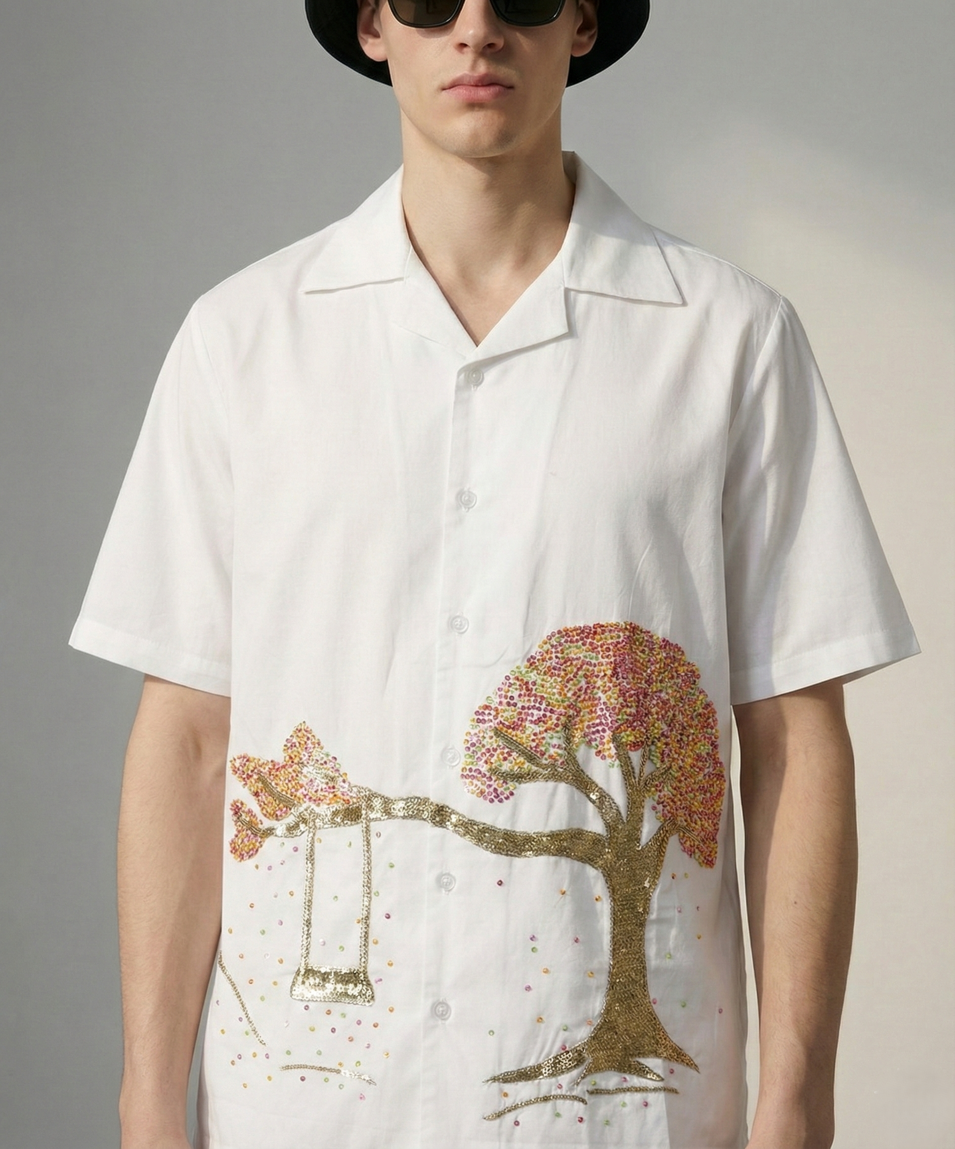 Close up of hand embroidered tree and swing artwork on white cotton Cuban collar shirt, detailed handmade embroidery design