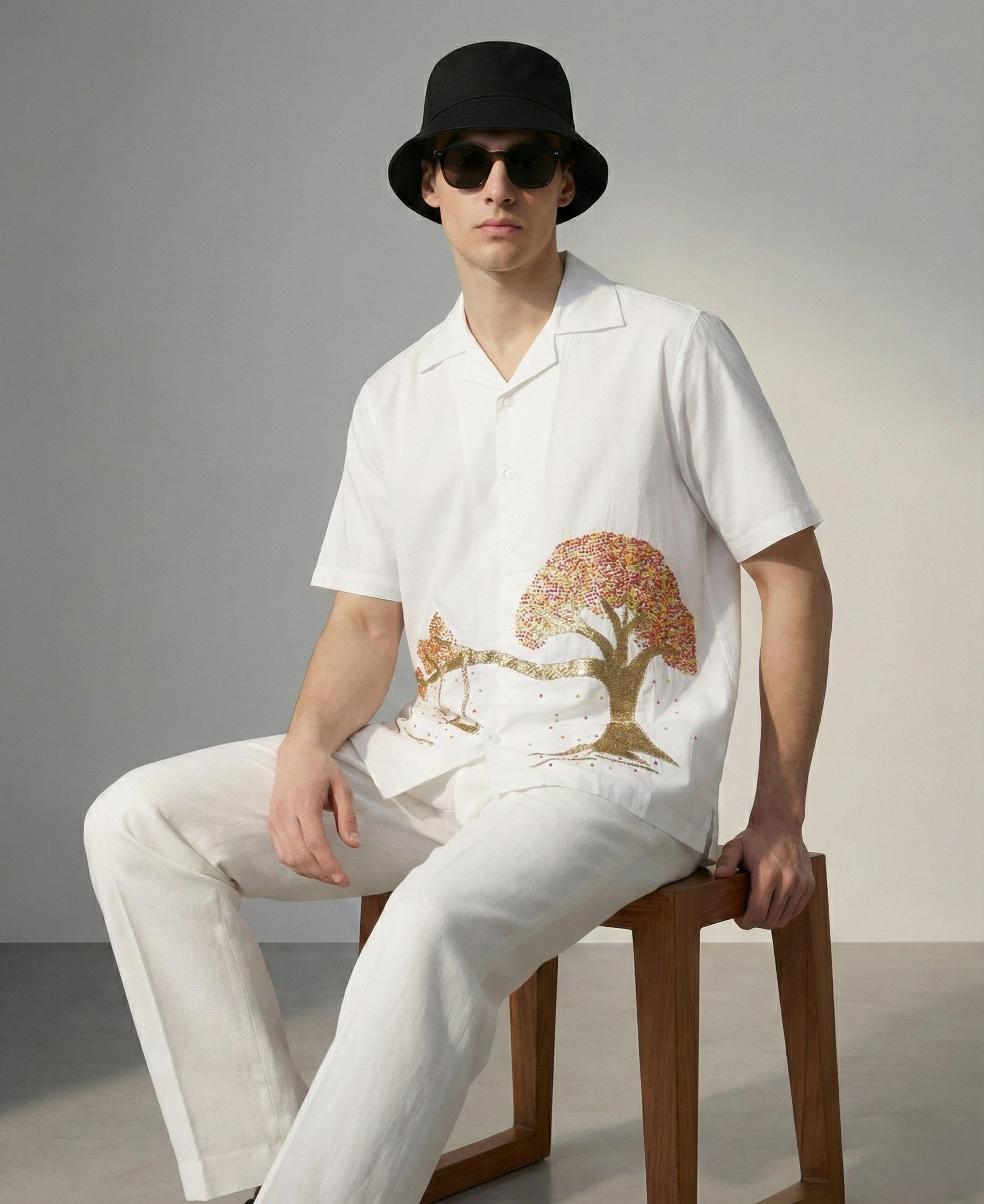 Man wearing white embroidered Cuban collar shirt with tree and swing design, stylish cotton summer outfit for men
