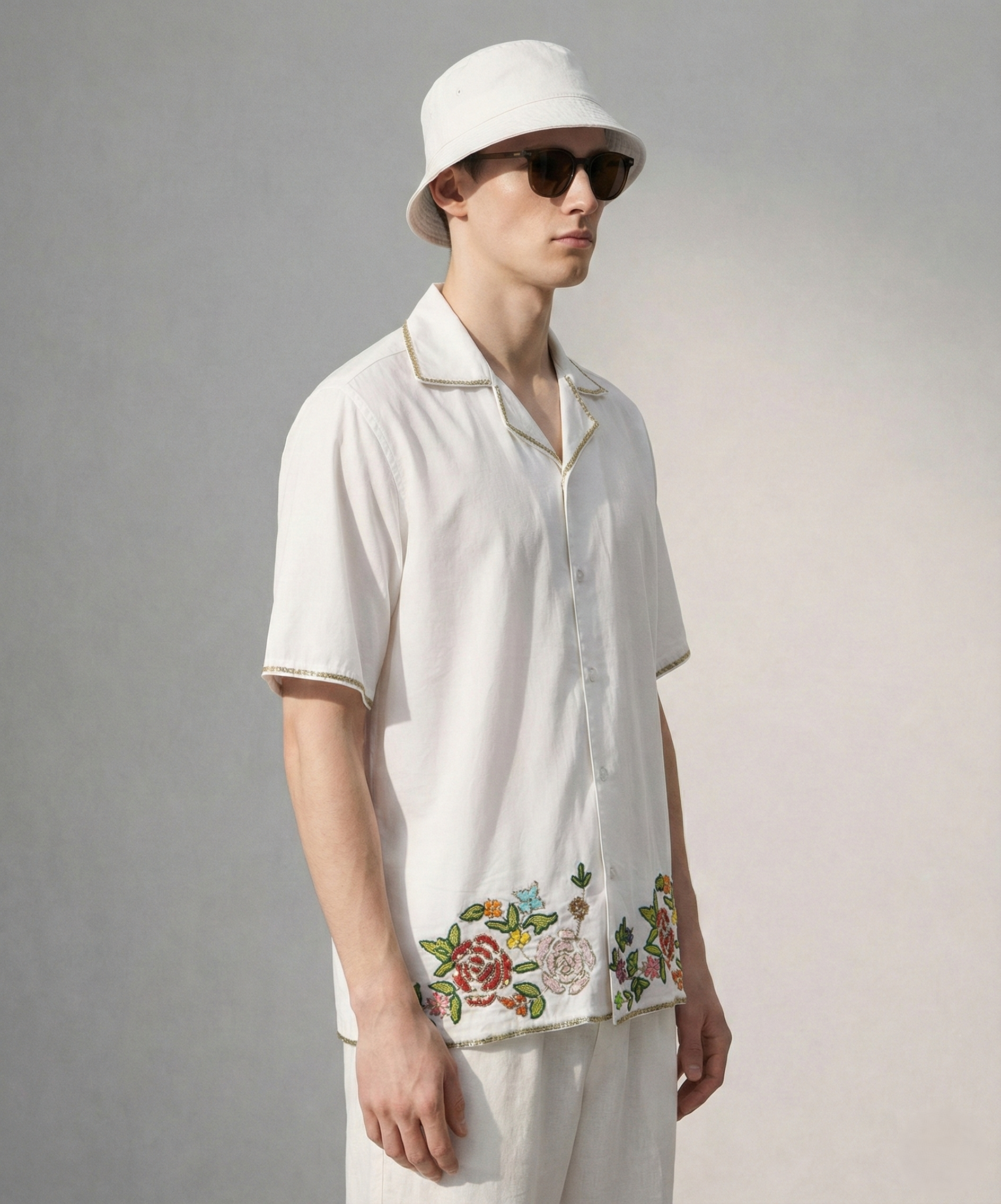 Side view of men's white Cuban collar cotton shirt with floral hand embroidery on hem, breathable summer vacation shirt for men