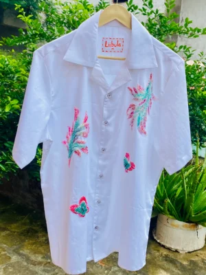 Full view of Le Butterfly Hand Embroidery Shirt, featuring white cotton fabric with vibrant hand embroidery, displayed outdoors on a hanger.