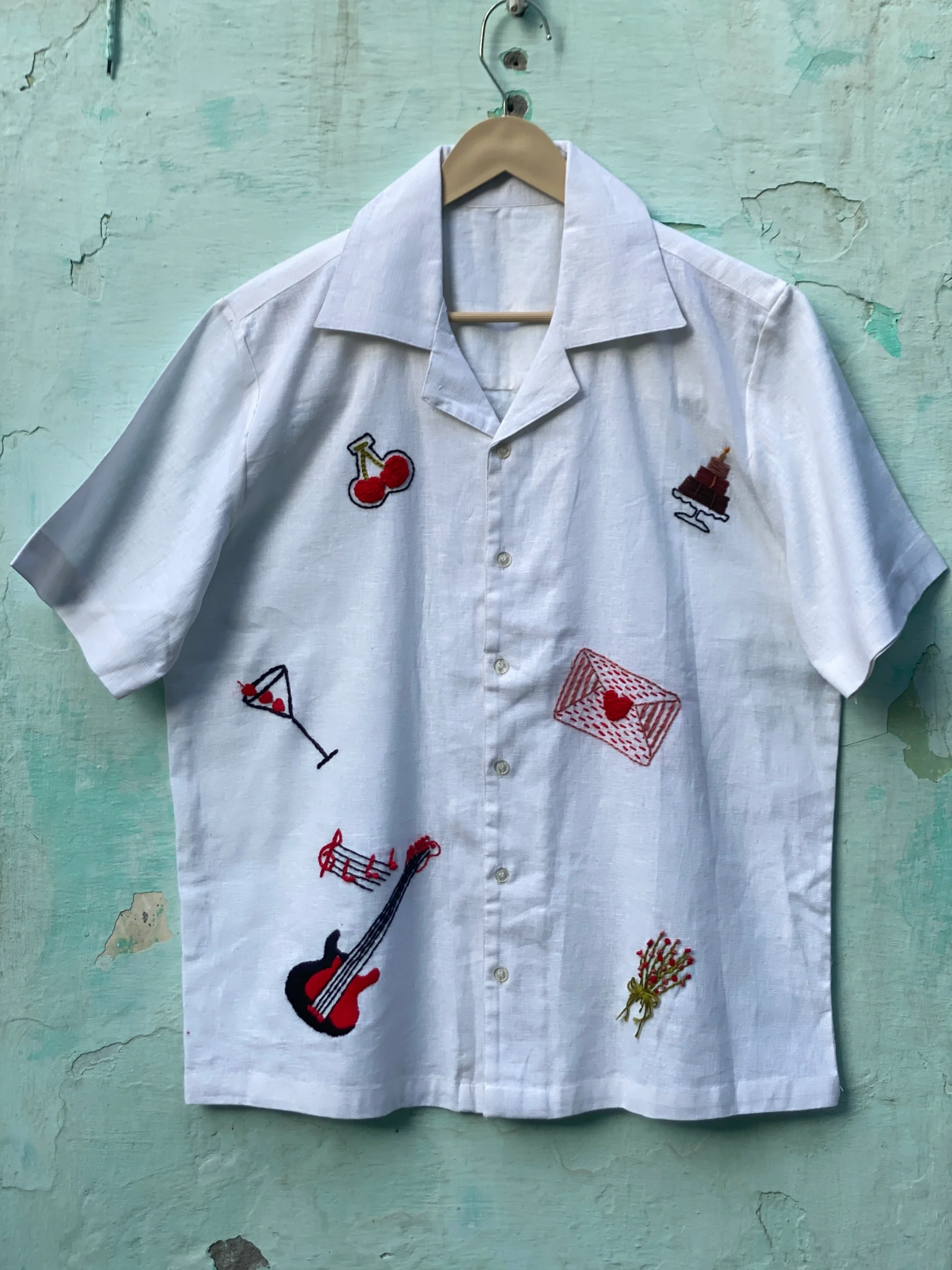 "Handmade linen cotton shirt with colorful hand embroidery including guitar, cherries, cake, and love motifs – limited edition Cuban collar shirt by Liibula"