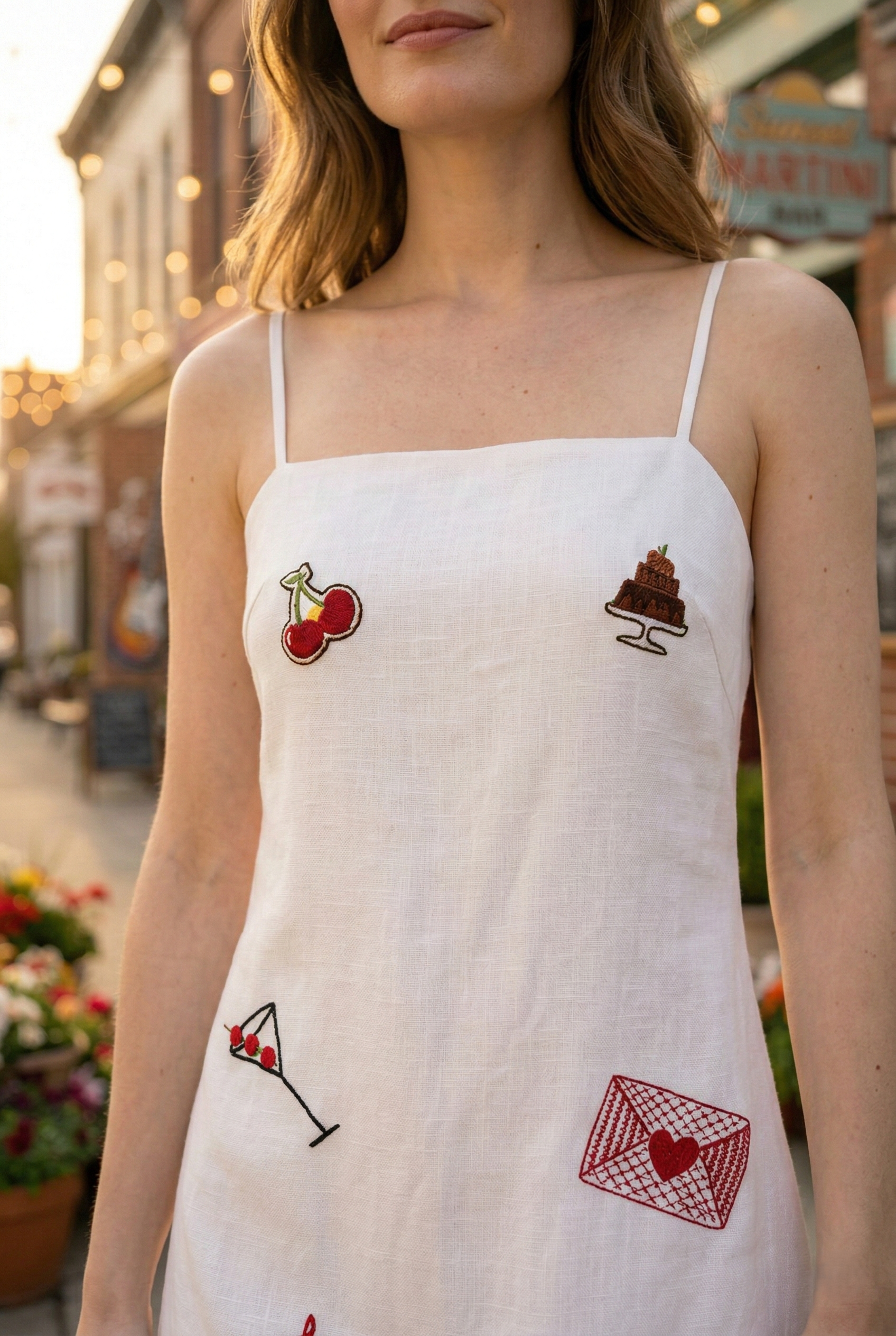 Close up embroidery detail on white summer dress with cherries cake and cocktail design