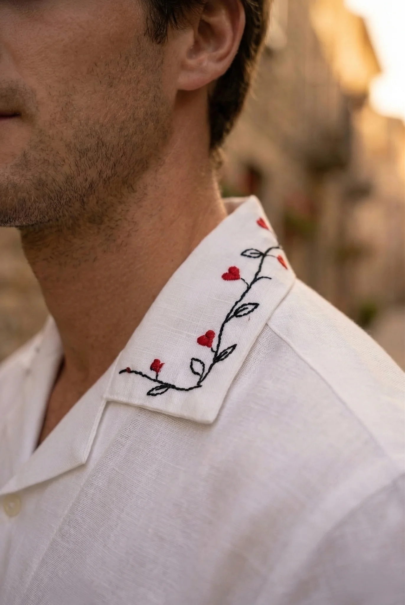 Close-up of shirt collar with red heart vine embroidery on white linen shirt, premium stitching detail, handmade luxury garment