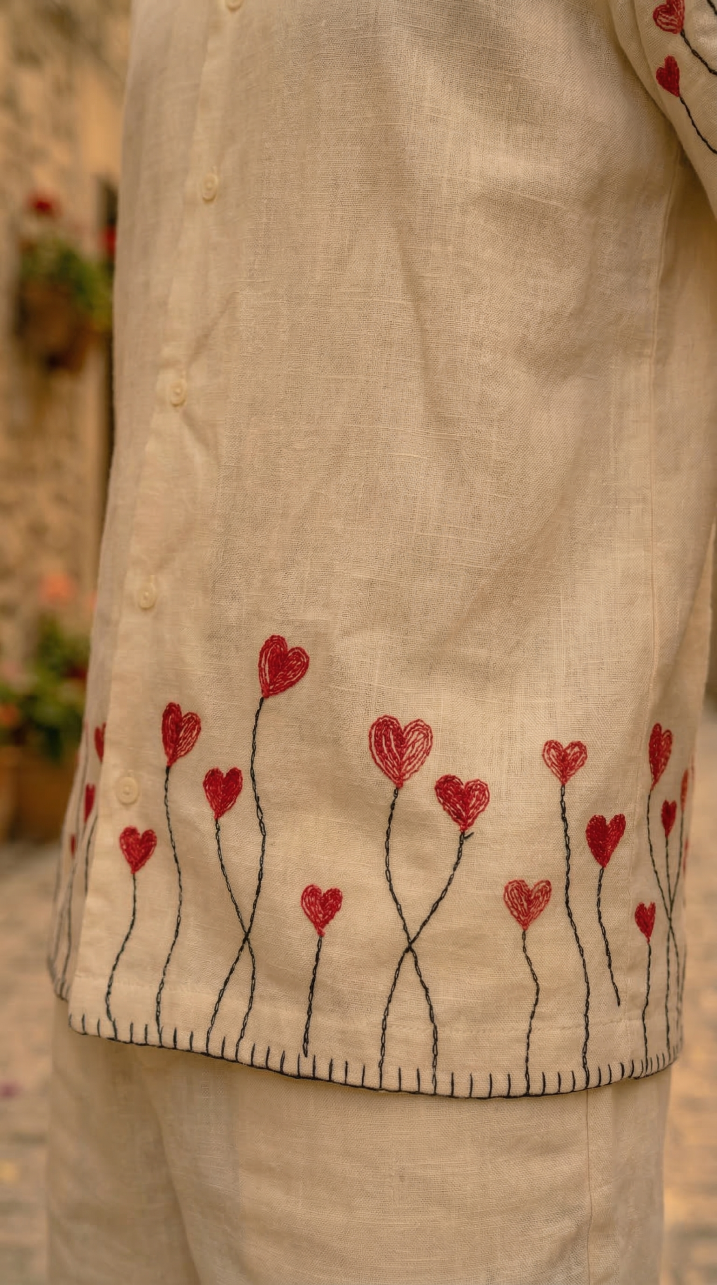 Close up red heart embroidery detail on linen shirt hem handmade design