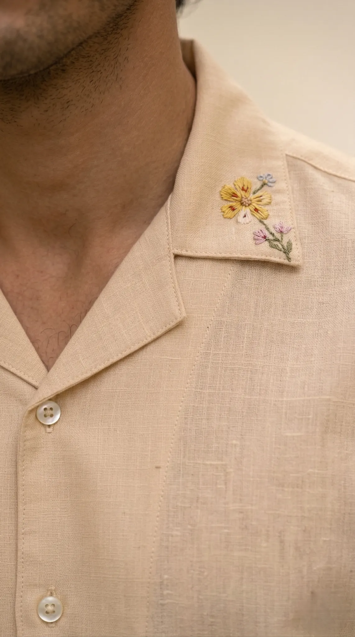 Closeup of beige linen shirt collar with delicate hand embroidery floral detail premium craftsmanship