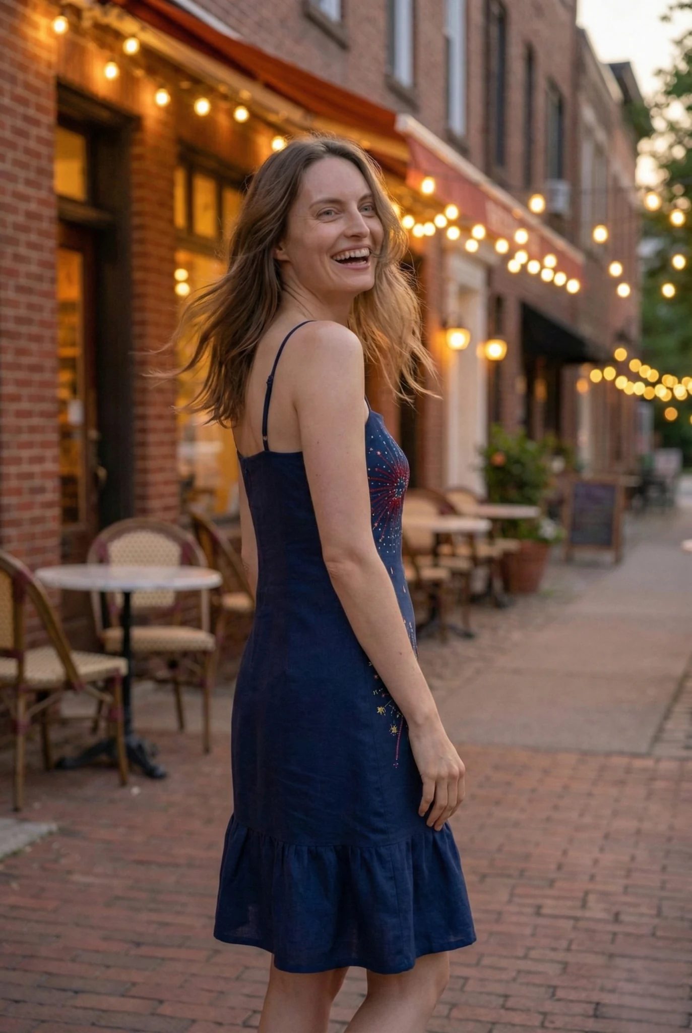 woman smiling wearing navy blue embroidered dress with colorful fireworks pattern relaxed summer outfit
